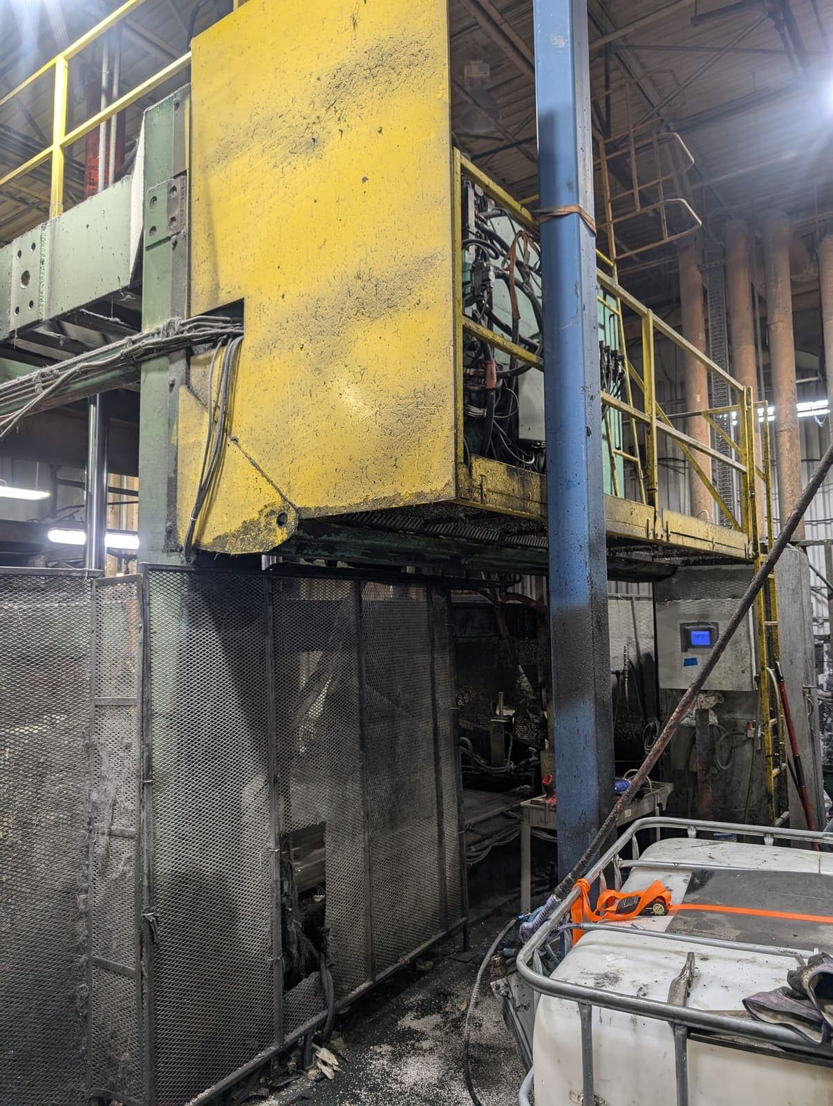 Équipement industriel à démanteler dans une usine, presse hydraulique jaune et structure métallique