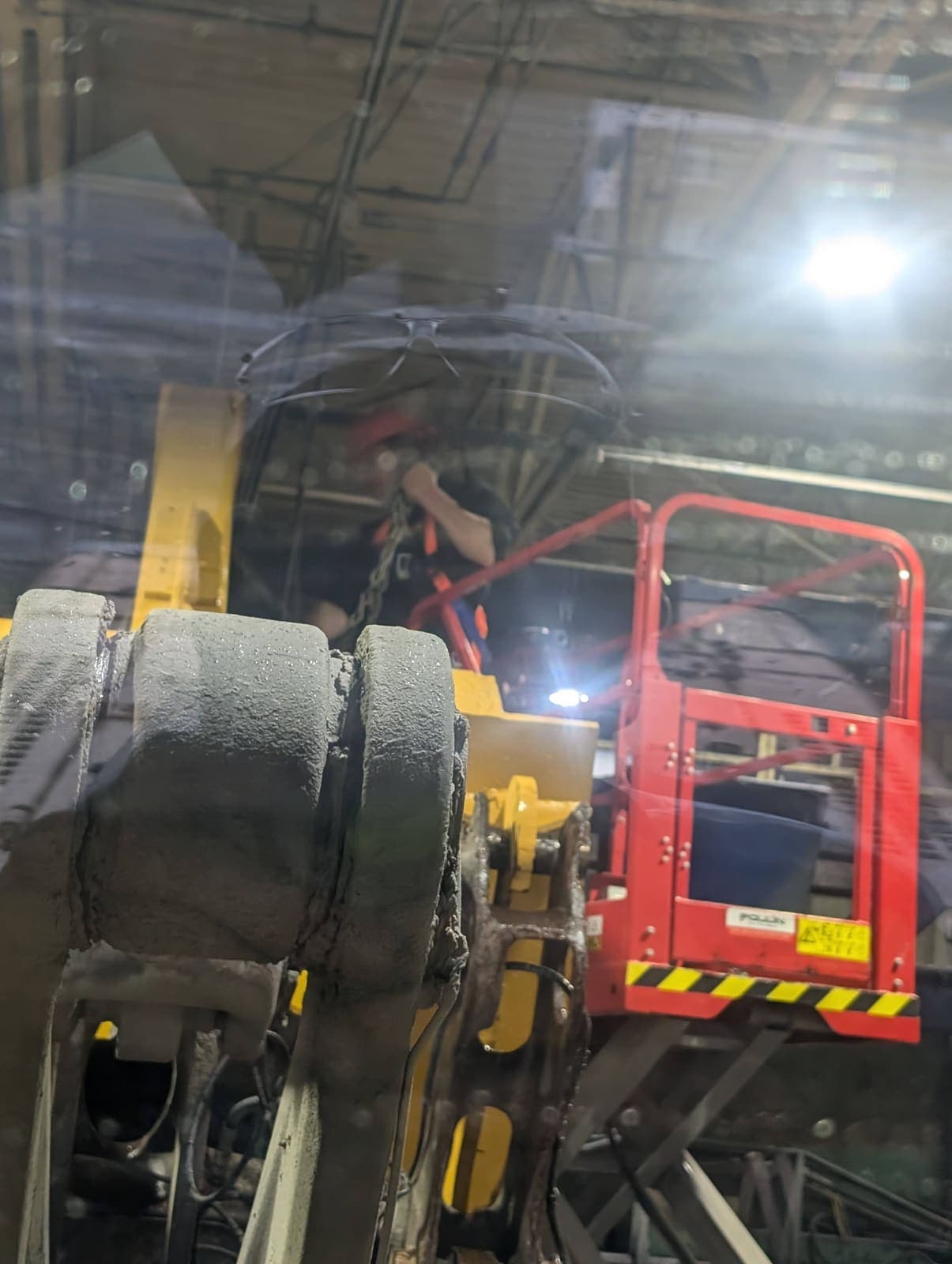 Vue intérieure du chantier de démolition à travers une vitre, opérateur dans une nacelle élévatrice rouge