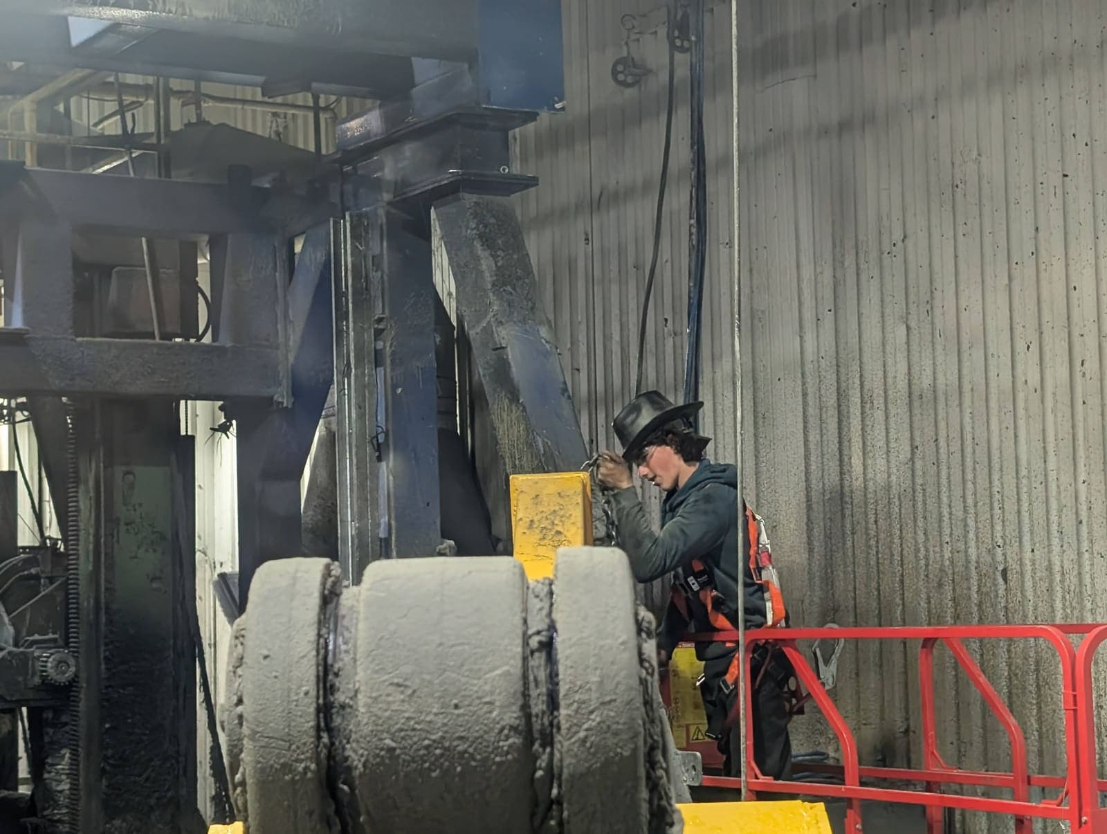 Ouvrier travaillant à la coupe d'une grosse pièce mécanique cylindrique en acier