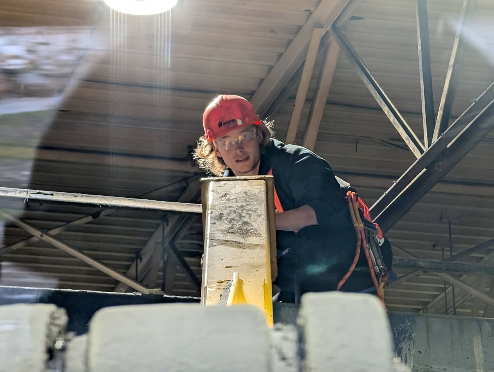 Ouvrier avec casque et harnais en hauteur, sur une poutre métallique de la structure à démolir