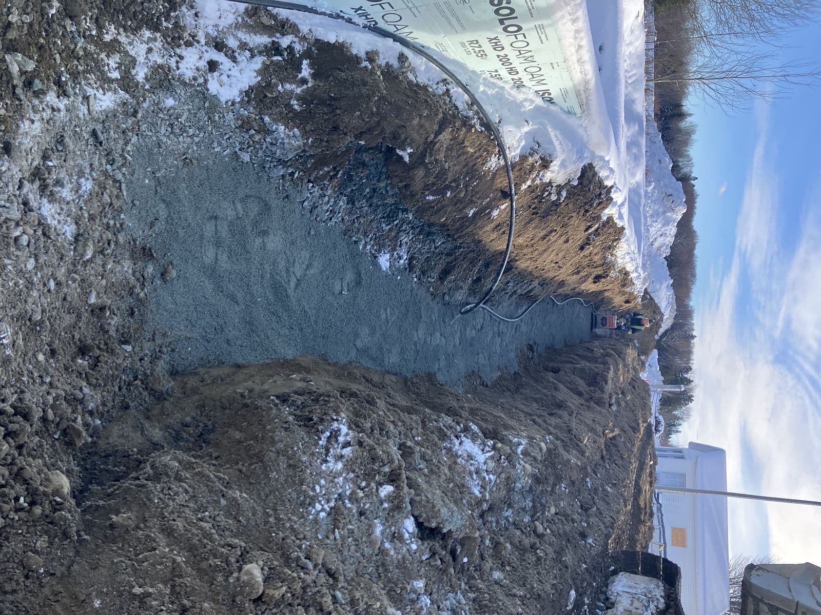 Tranchée de drainage profonde avec panneaux d'isolant rigide et lit de gravier compacté en bordure d'un bâtiment