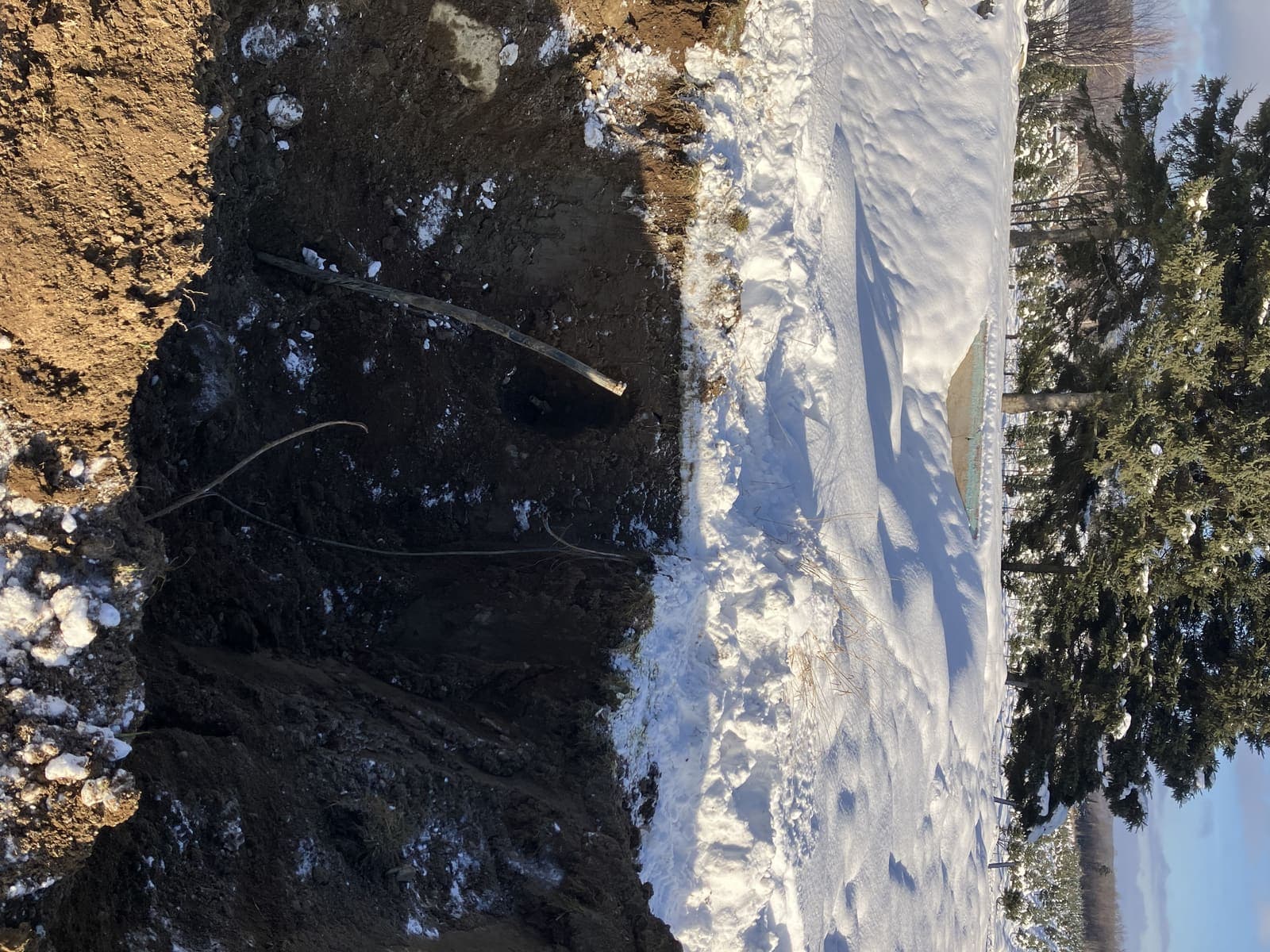Tranchée de drainage profonde recouverte partiellement de neige, paysage hivernal à Adstock