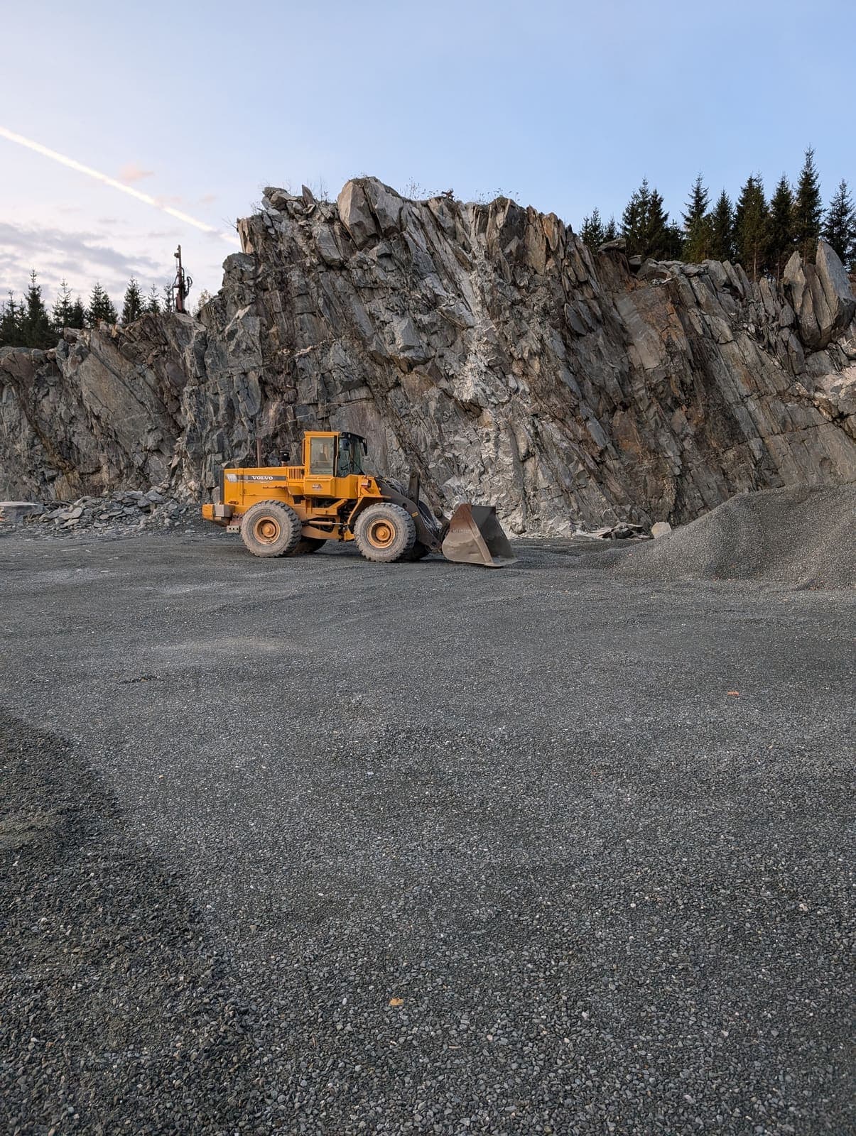 Chargeuse sur roues devant la grande paroi rocheuse de la carrière