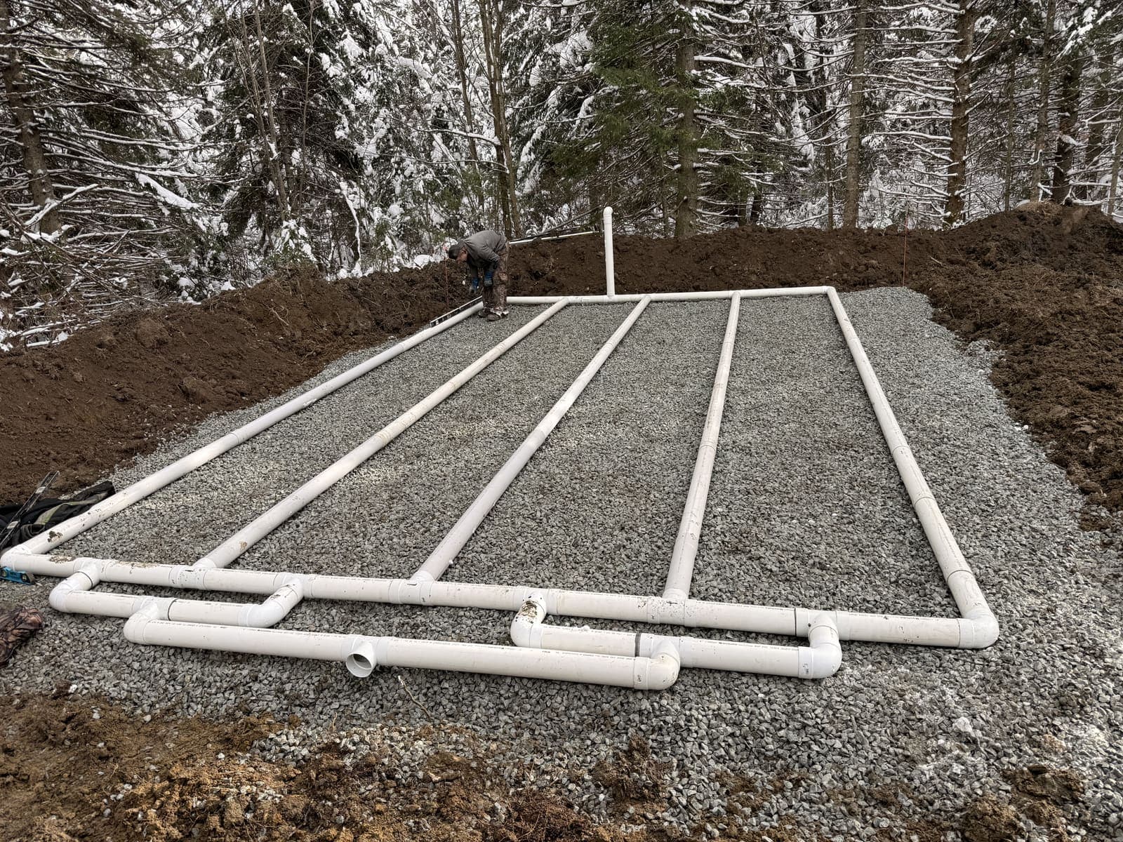 Champ de polissage septique avec conduites PVC blanches sur lit de gravier devant une forêt enneigée à Thetford Mines