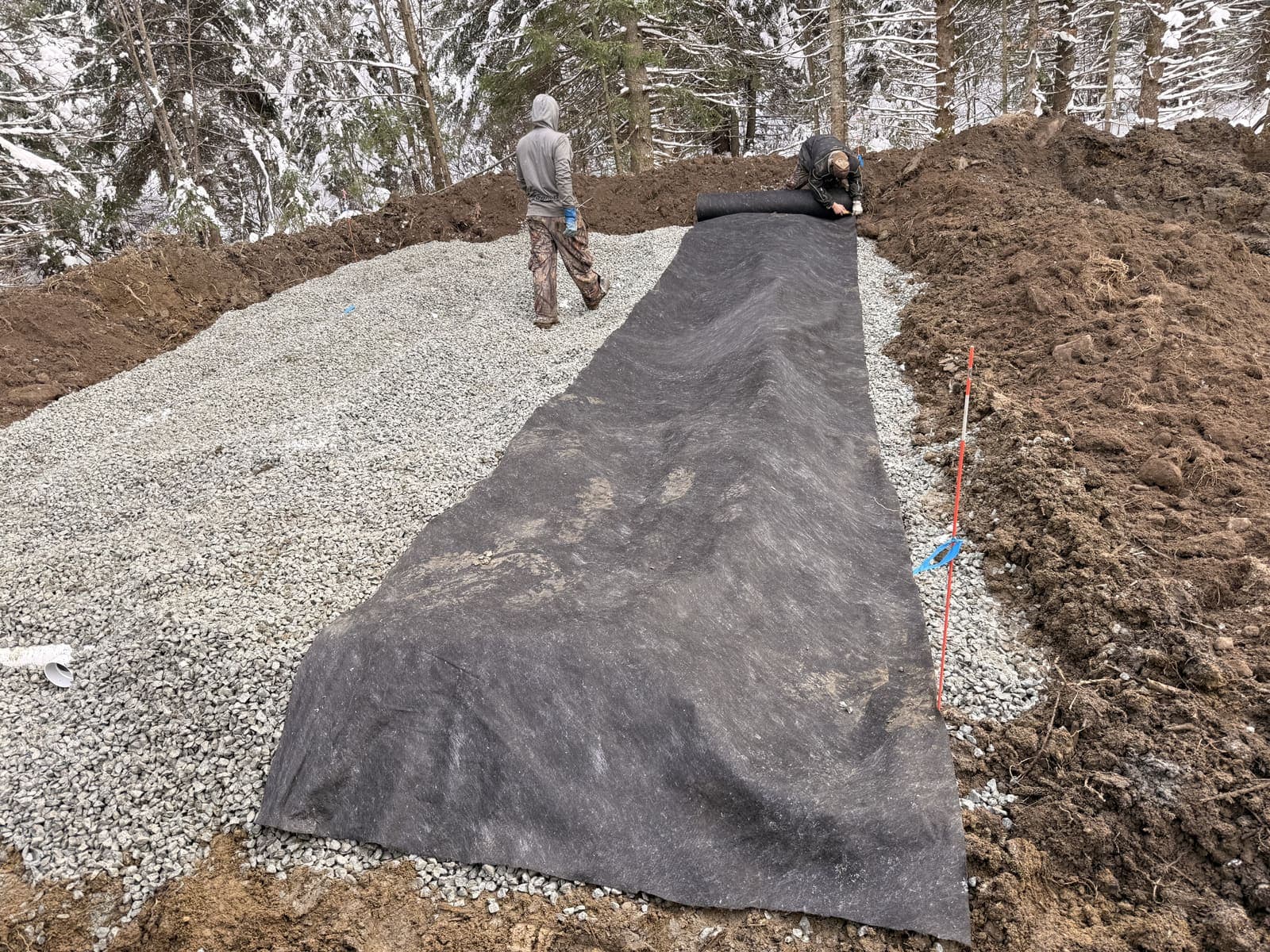 Pose d'une membrane géotextile par-dessus le champ de polissage en conditions hivernales