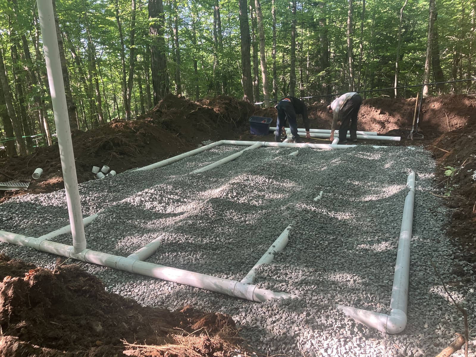 Champ de polissage avec conduites PVC sur lit de gravier en pleine forêt, équipe d'A.L.O Pomerleau au travail