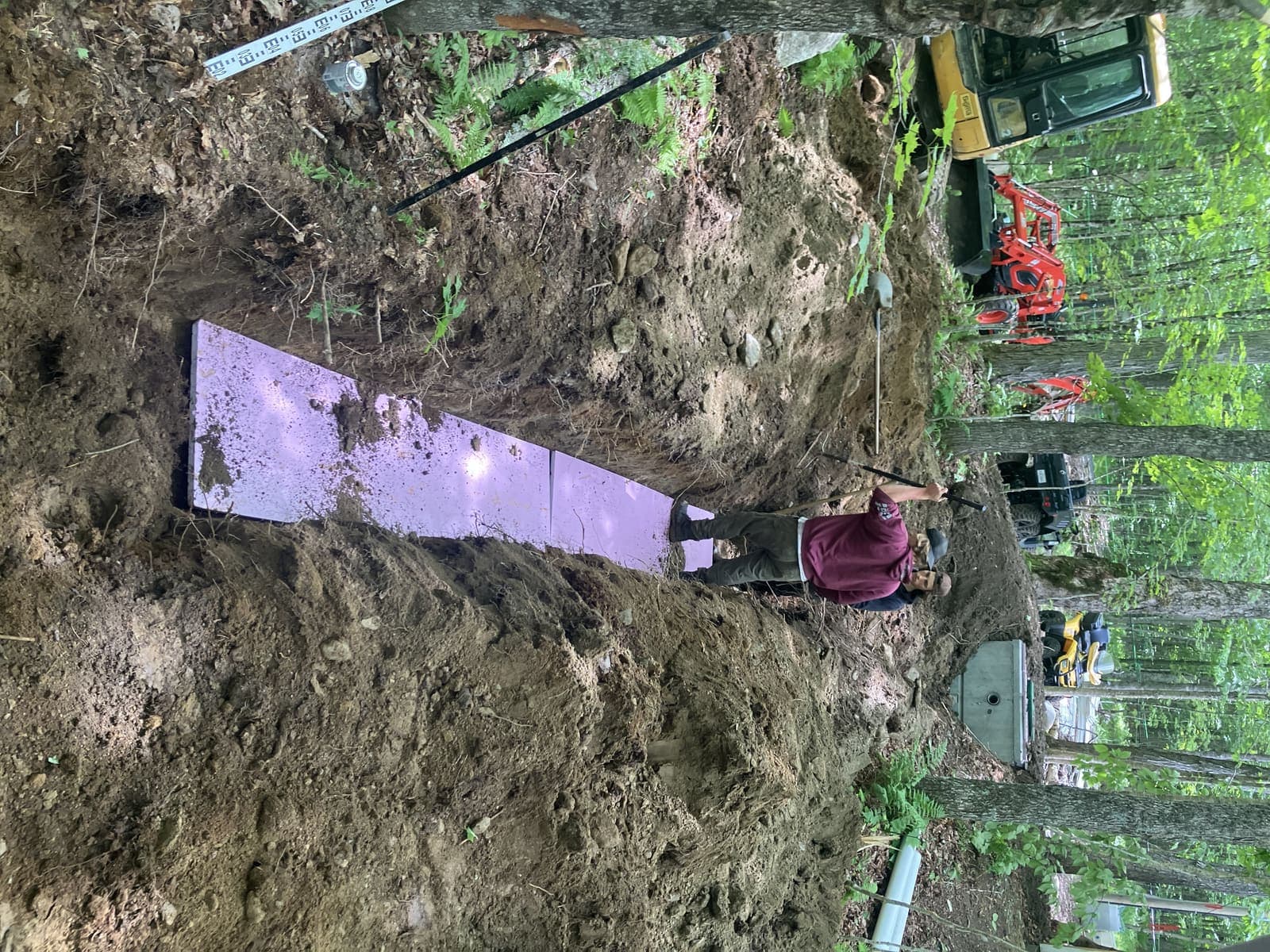 Pose de panneaux d'isolant rigide dans une tranchée septique avec mini-pelle Kubota en arrière-plan