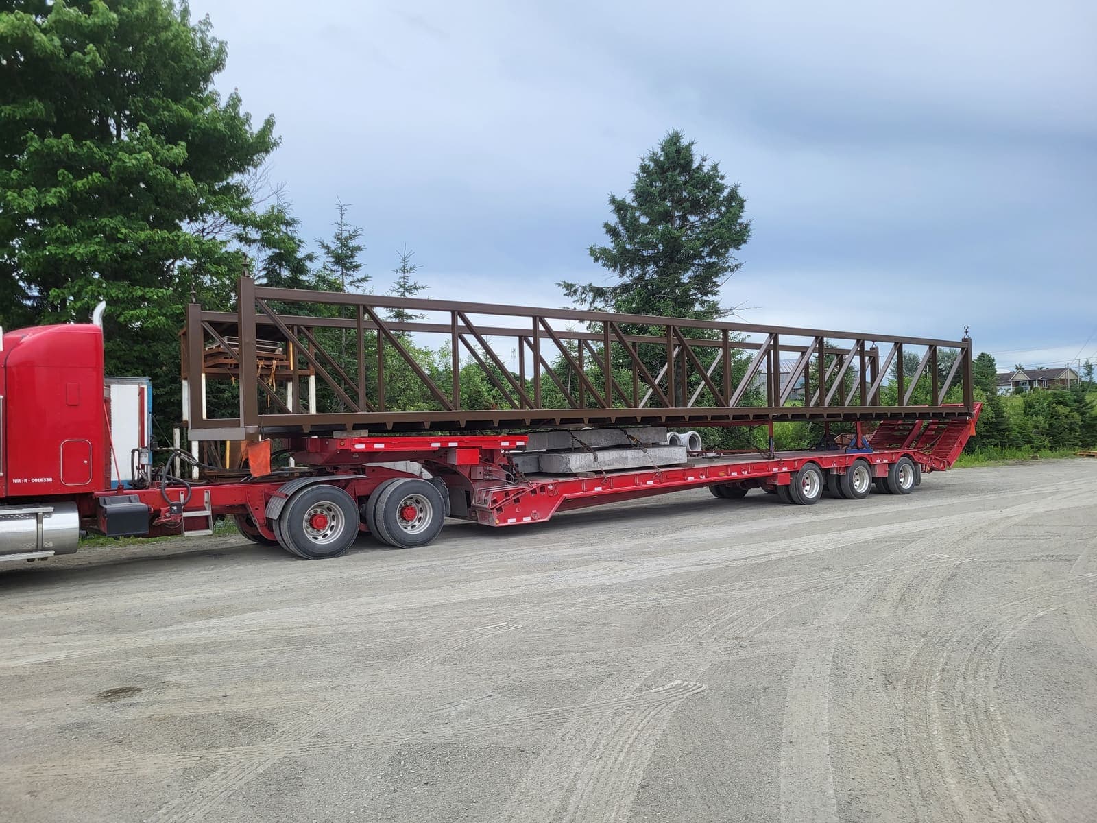 Vue latérale d'une longue charpente métallique brune sur fardier extensible