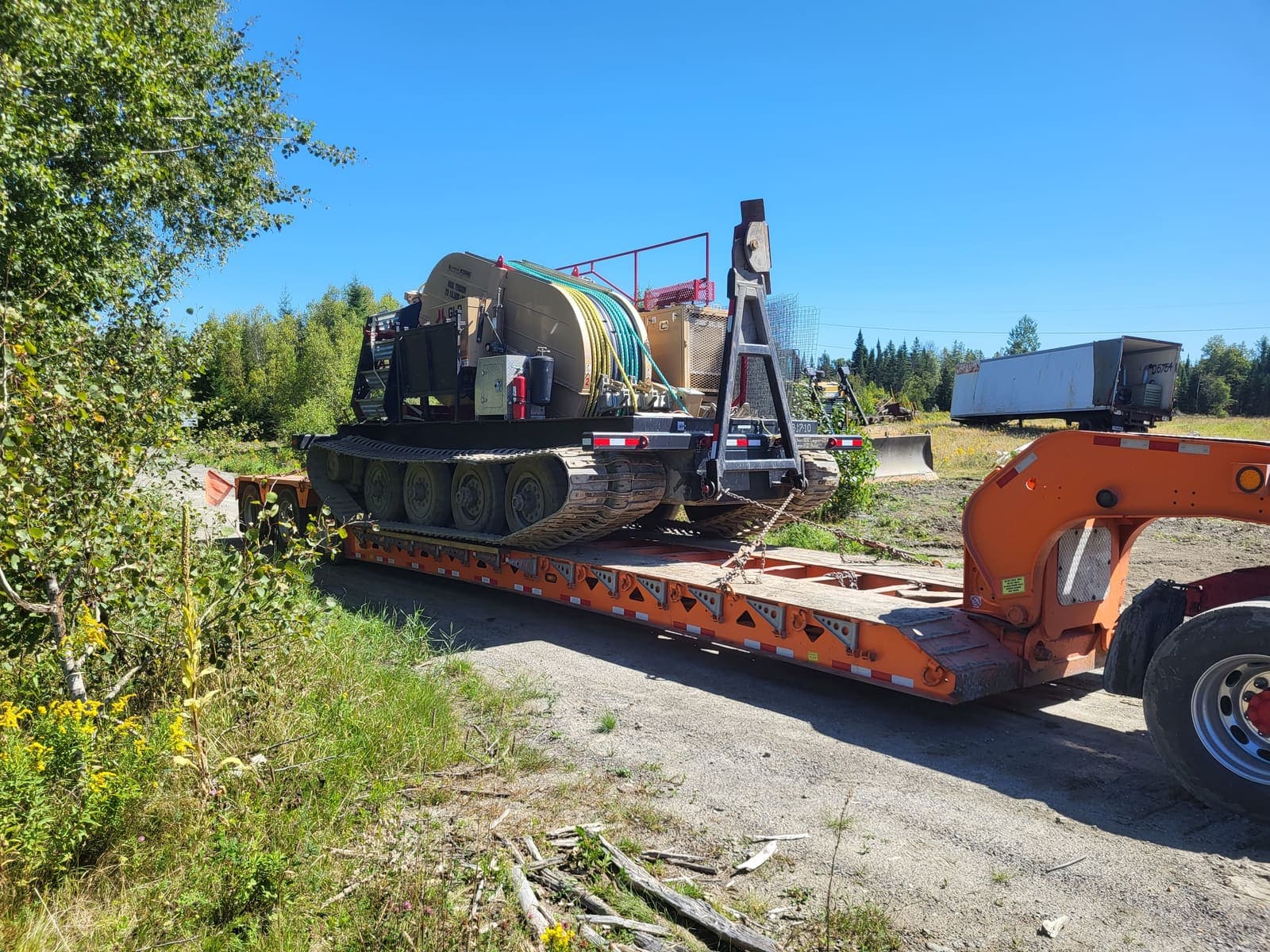 Véhicule chenillé sur fardier dans une clairière forestière