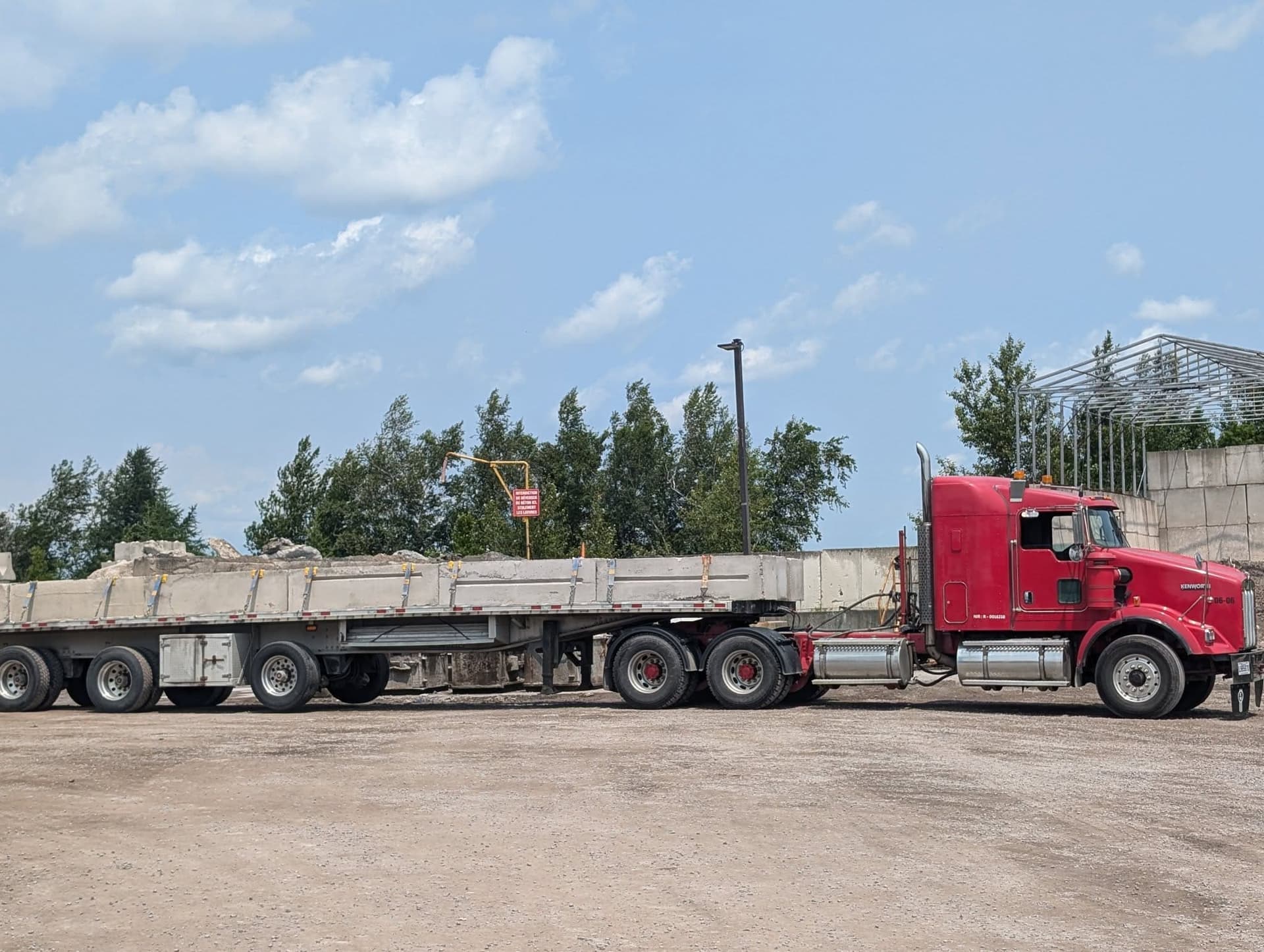 Camion Kenworth rouge transportant des blocs de béton préfabriqués — A.L.O Pomerleau